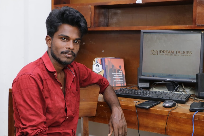 A portrait of the young, male filmmaker in front of his computer. 