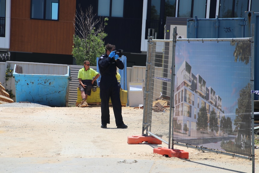 A forensics police officer taking a photo of a construction site
