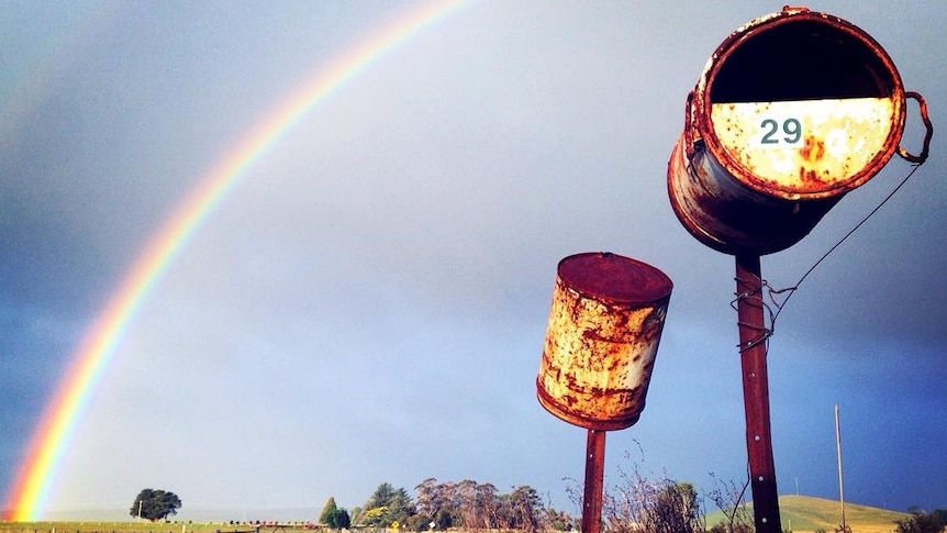 A rusted letterbox under a rainbow in rural Victoria