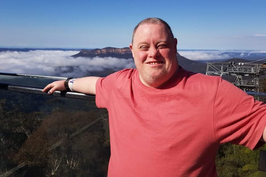 Leigh Creighton standing at a lookout with a mountain in the distance behind him.
