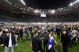 Spectators gather on the pitch after France-Germany international soccer match at Stade de France.