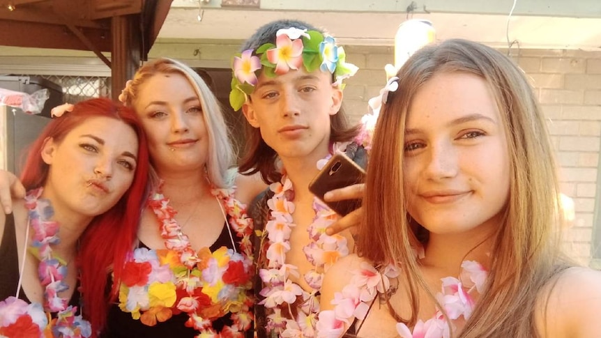The four siblings smile in a selfie, wearing Hawaiian lays.