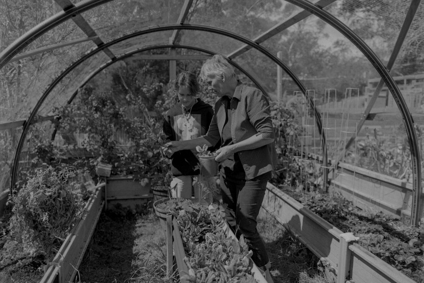 A woman and a girl tend to a garden 