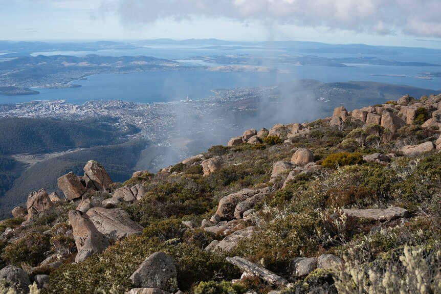 looking down the side of mount wellington, rocks and bushes, down to hobart 