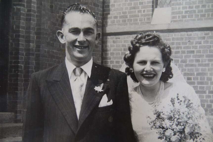An historic black and white photo of a bride and groom grinning out the front of a touch