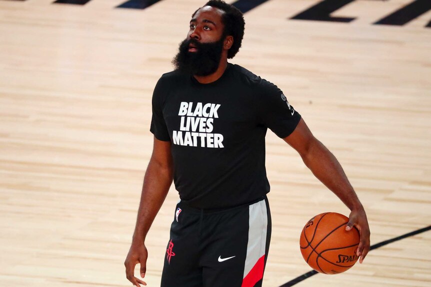 James Harden looks up while dribbling a ball in warm up. He is wearing a Black Lives Matter shirt.