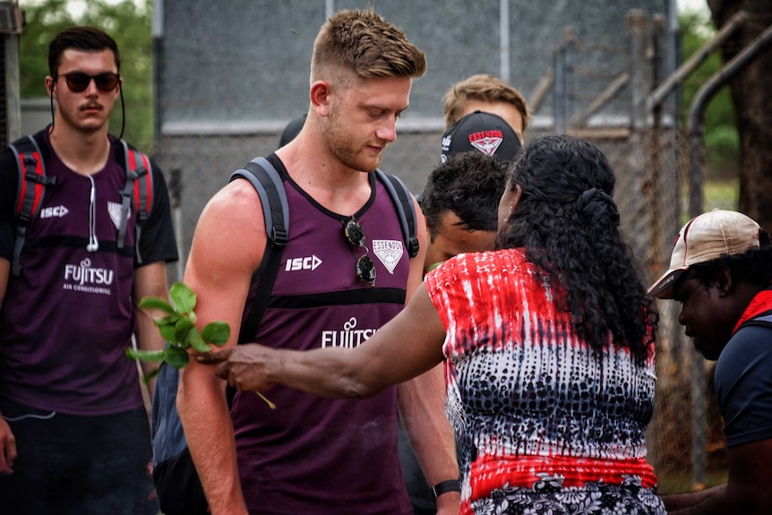Mary Dunn touches the arms of Jayden Laverde with branches during a smoking ceremony.