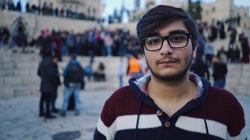 College student Adnan Bark stands in front of a crowd of people