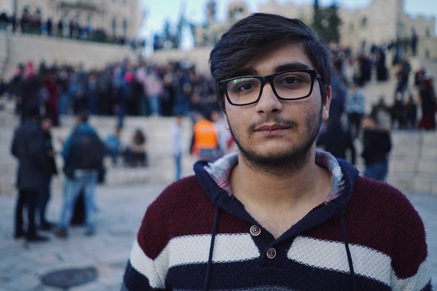 College student Adnan Bark stands in front of a crowd of people