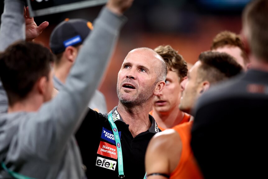 GWS caretaker coach Mark McVeigh looks up at a whiteboard while addressing players during a game.