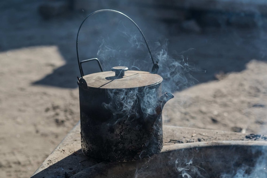 A kettle sits on the edge of the fire pit