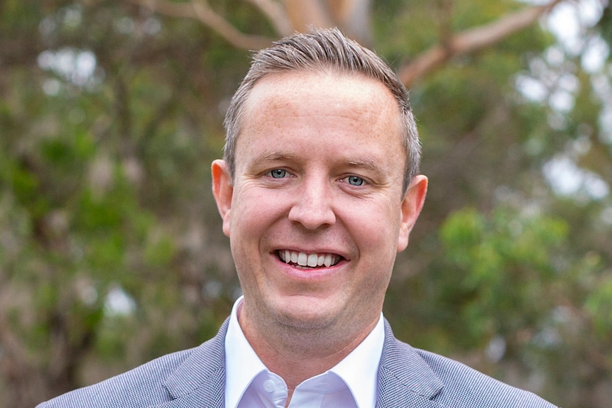 A smiling man with greying hair, wearing a suit.