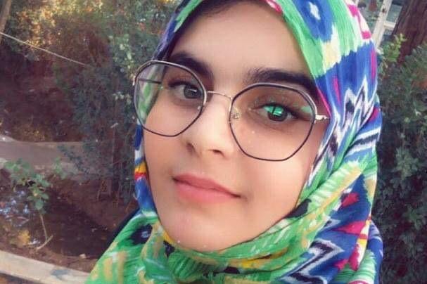 A young woman wears glasses and a colourful headscarf.