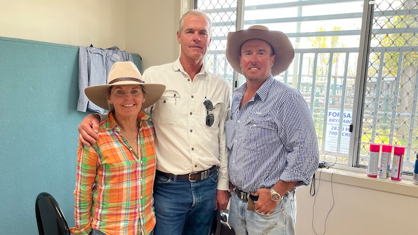 A woman and two men stand smiling