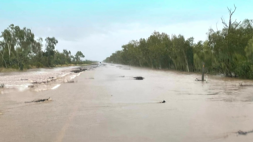 A road in outback Australia flooded over by brown water