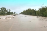 A road in outback Australia flooded over by brown water