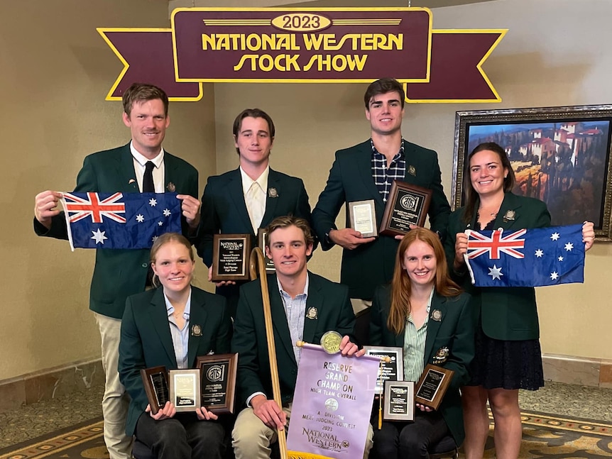 A group of five young people grin in formal green team uniforms holding ribbons and Australian flags.