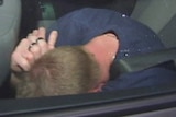 Adrian Bayley covers his face in the back seat of a car