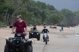 Some young men on quad bikes and a motorbike riding on a beach