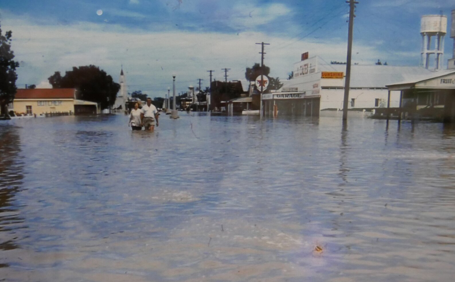 file photo of a flooded street with people wading in the water