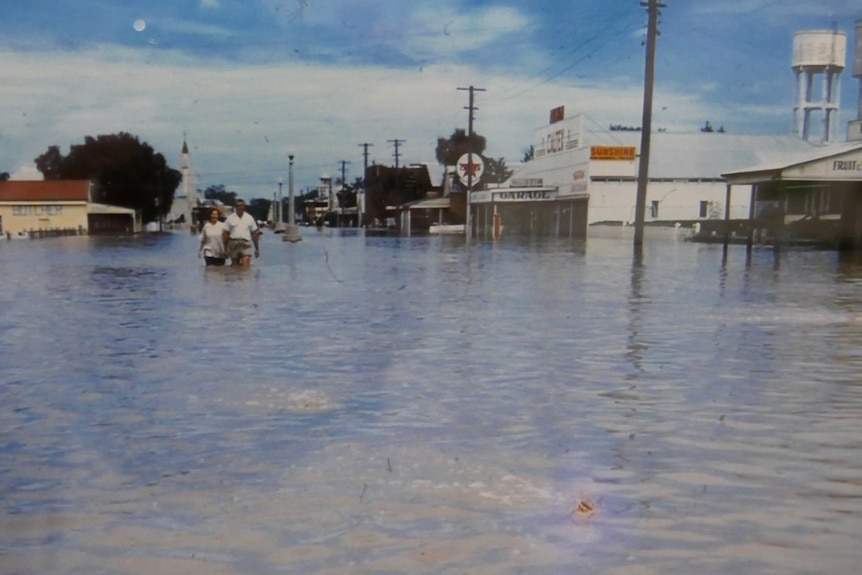 file photo of a flooded street with people wading in the water