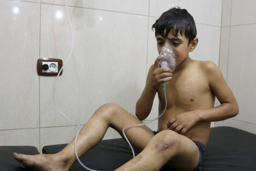 A Syrian boy suffering from breathing difficulties applies a breathing mask.