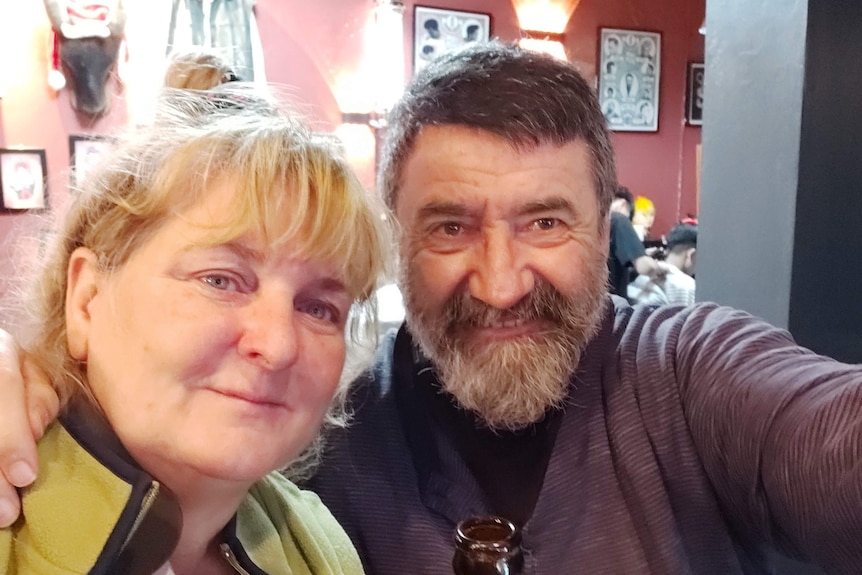 A middle-aged couple take a selfie in a restaurant.