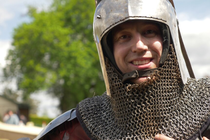 Buhurt figher Marcus Huber smiles, in his full set of armour