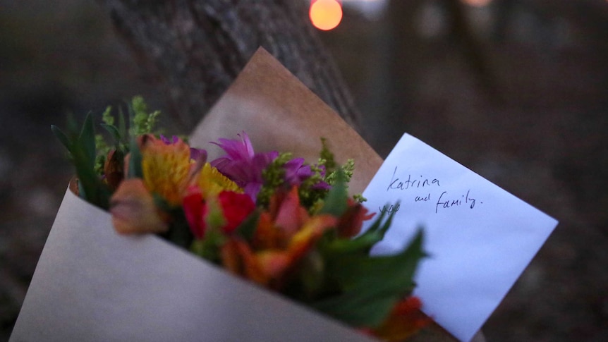 Flowers with a card addressed to Katrina and family placed next to a tree outside the Osmington property.