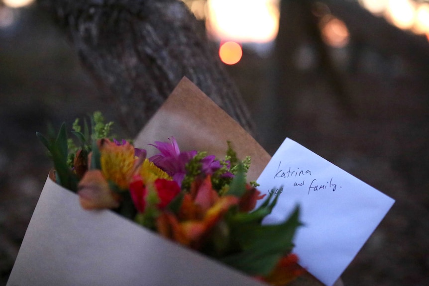 Flowers with a card addressed to Katrina and family placed next to a tree outside the Osmington property.