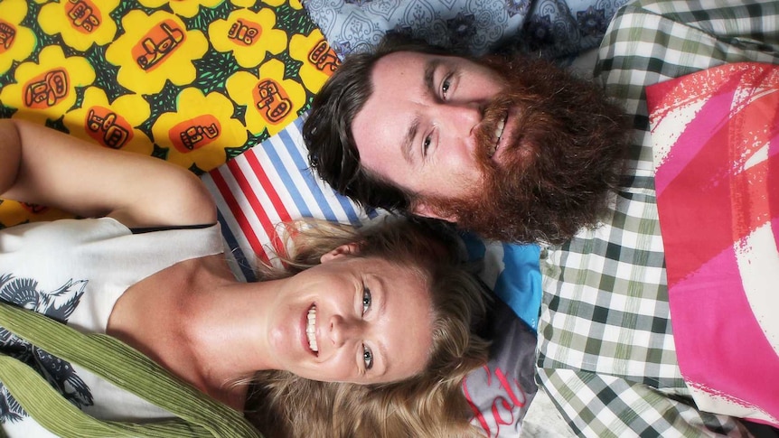 Megan Rowlatt and Adam Woods lay on the ground surrounded by Boomerang Bags.