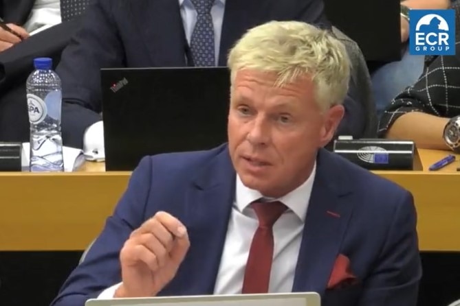 A man sitting at a desk asking a question.