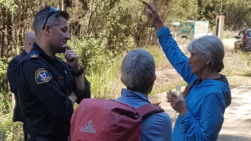 The wife of the missing bushwalker, right, talks with police