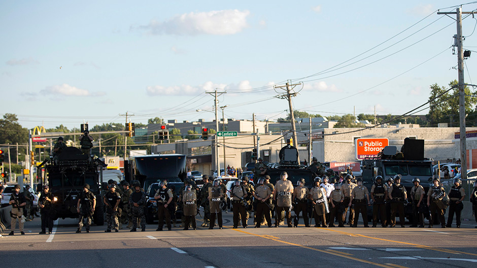 Police in riot gear block the street in the US town of Ferguson after a shooting of a black teenager by a police officer.