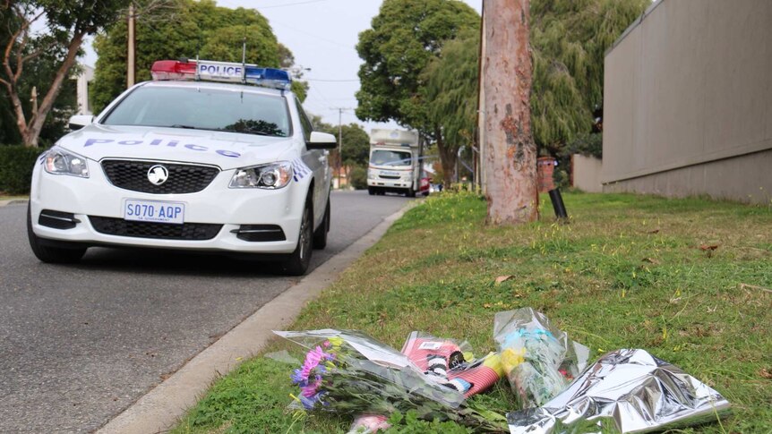 Flowers left in the street near the Walsh home and a nearby police car in view