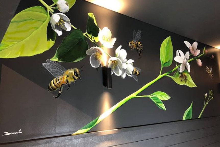 A mural of bees flying around flowers and greenery on a wall