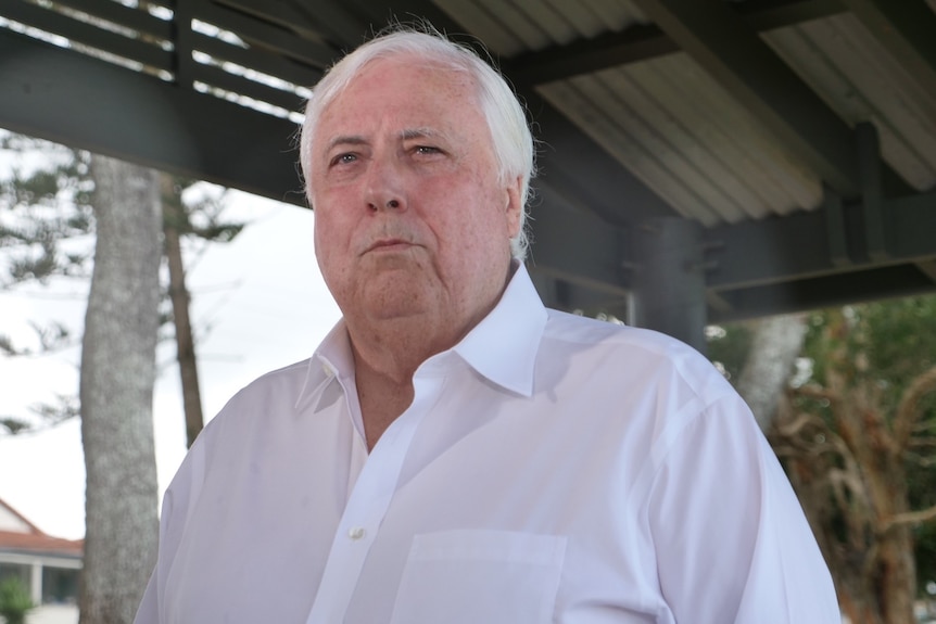 Clive Palmer with white shirt and white hair, rain drops on camera lens against overcast suburban Gold Coast