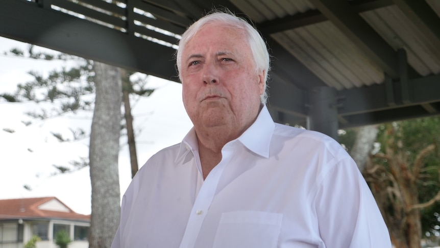 Clive Palmer with white shirt and white hair, rain drops on camera lens against overcast suburban Gold Coast