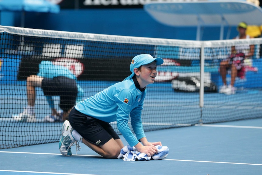 A ball boy wipes the court at the Australian Open.