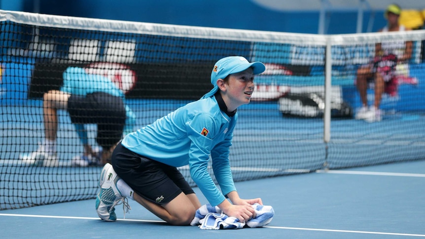 A ball boy wipes the court at the Australian Open.