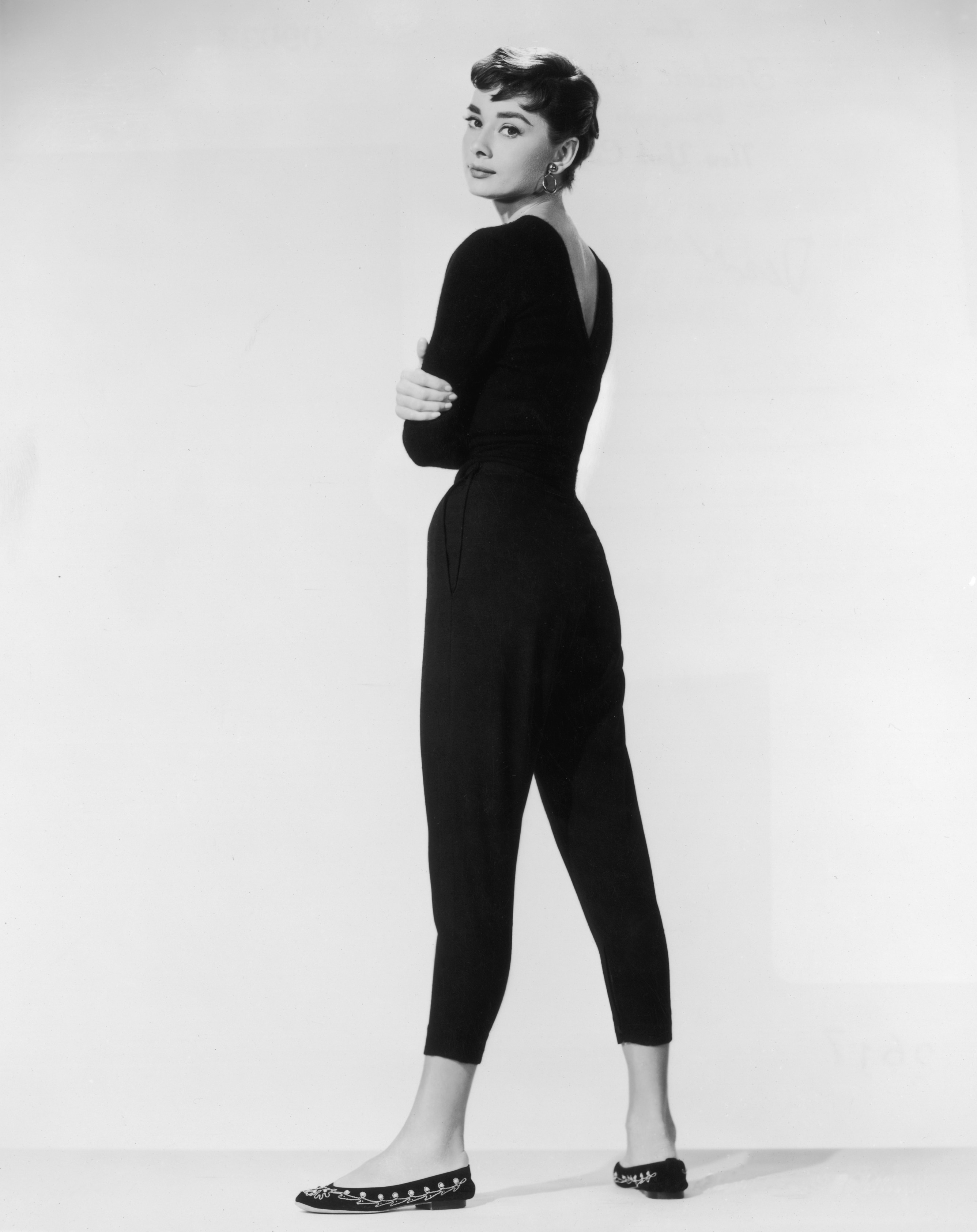 Audrey Hepburn wears capri pants and looks over her shoulder towards the photographer