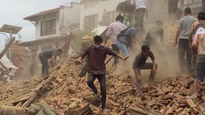 A man climbs down pile of rubble after Kathmandu earthquake