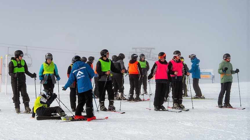 A group of skiers gathered at the top of a ski course