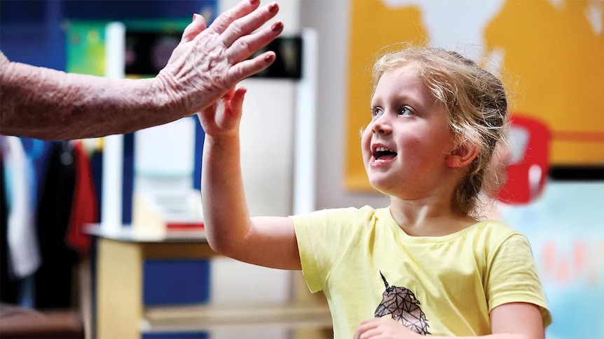 Young child giving a high five to an elderly adult