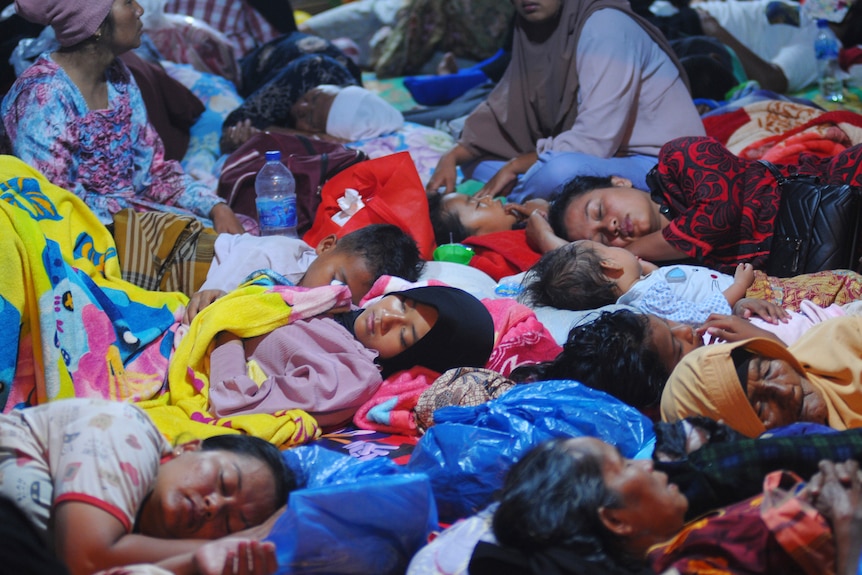 Earthquake survivors sleep inside a tent at a temporary shelter.