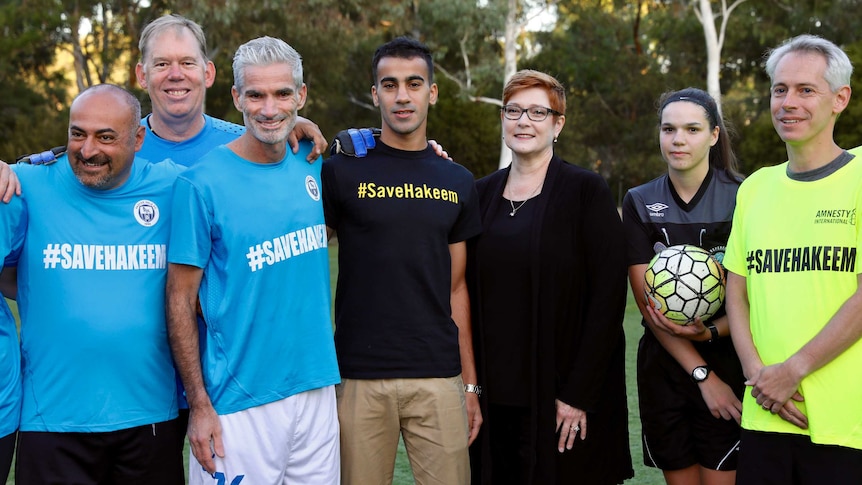 A man is surrounded by cheering soccer players and dignitaries after a match at Parliament House.