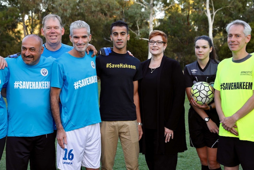 A man is surrounded by cheering soccer players and dignitaries after a match at Parliament House.