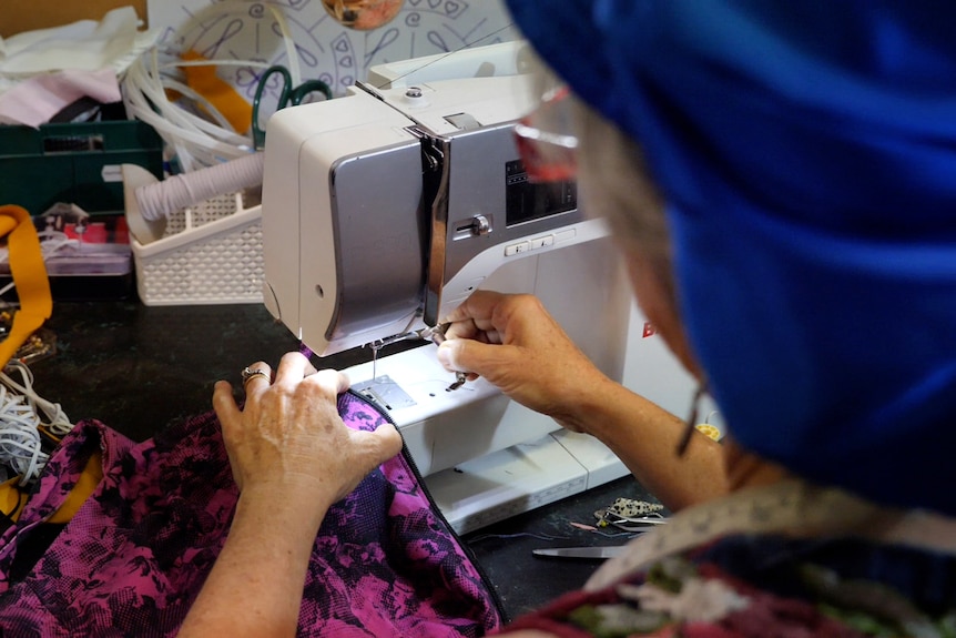 Ms Mylrea with her back to the camera as she works at her sewing machine.