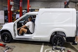 Workers sit in two-seater electric van called the 'Cargo' being built in a Logan warehouse.