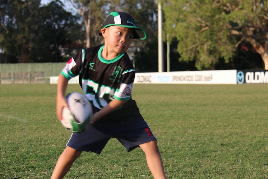 A young boy passing a rugby ball
